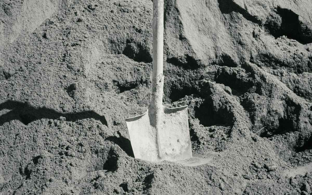 Heap of fine grey sand with a shovel — stock photo