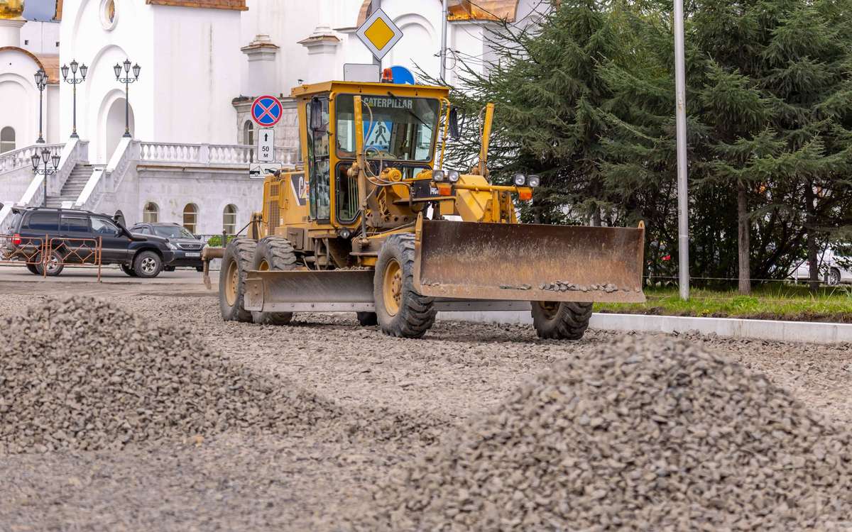 Road grader spreading crushed stone on a road under construction — stock photo