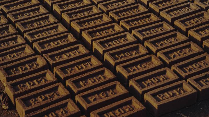 Rows of red clay bricks laid out on the ground